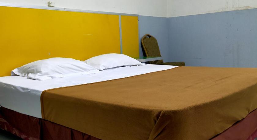 two beds in a room with a blue wall, Hotel Nirwana Ternate RedPartner in Ternate
