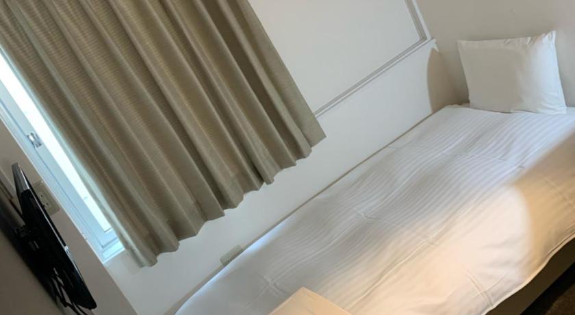 a bed in a room with a window, Hotel Oxio in Okayama