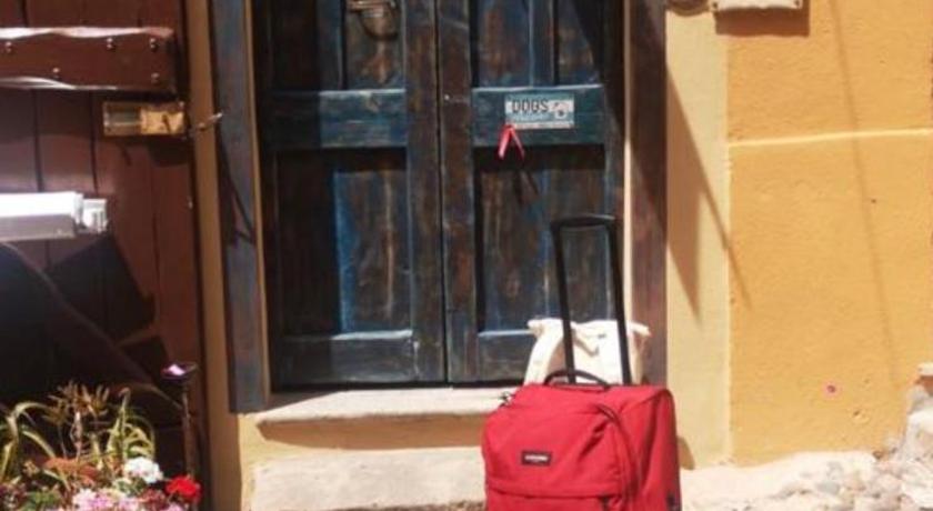 a red suitcase sitting on the sidewalk next to a red door, Aigua in Alghero