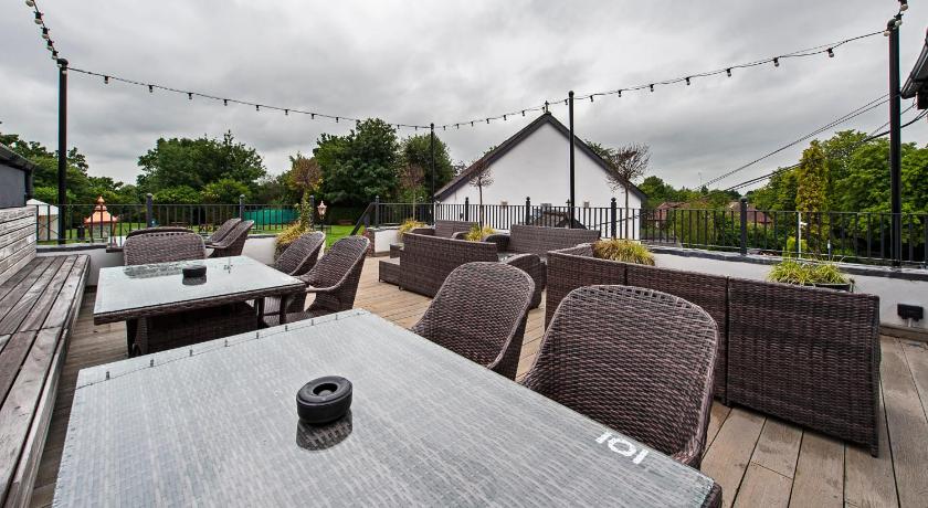 a patio area with tables, chairs and umbrellas, The Bulls Head And Lodge in Manchester