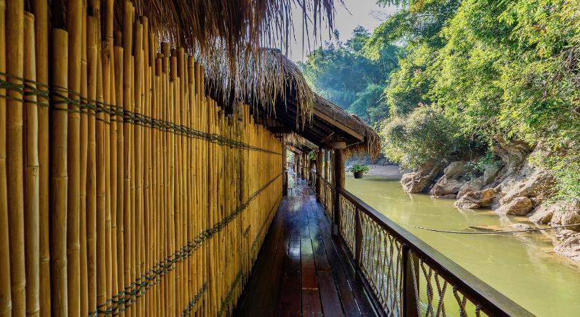 a wooden bridge over a river next to a forest, The Float House River Kwai Resort (SHA Extra Plus) in Kanchanaburi