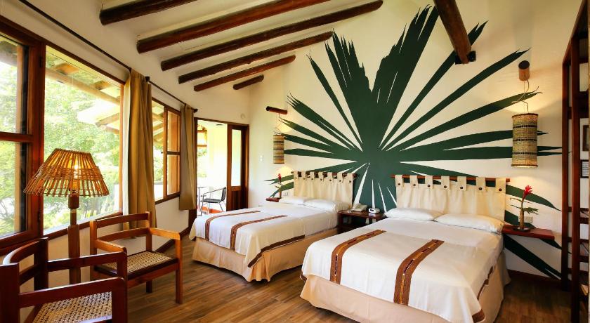 a hotel room with two beds and a canopy, Villa Maya in Flores