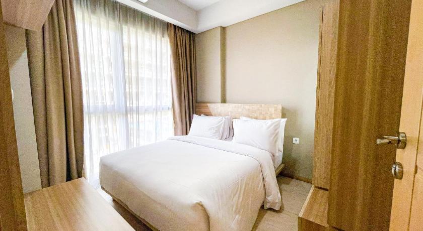 a bedroom with a bed and a dresser, Graha Makara Suite Hotel and Residence in Cikarang