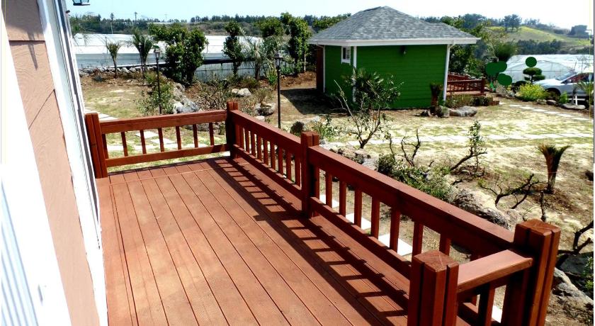 a wood decked deck with a wooden railing, Jubilee Pension in Jeju