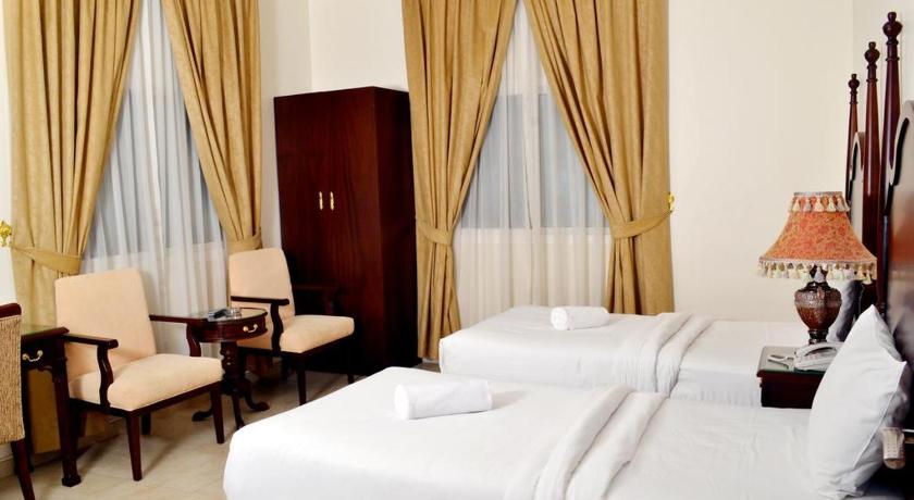 a hotel room with two beds and a chair, Sara Hotel Apartments in Ajman