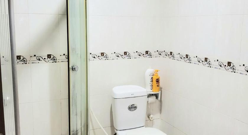 a white toilet sitting next to a shower in a bathroom, Cozi 5 Service Apartment in Ho Chi Minh City