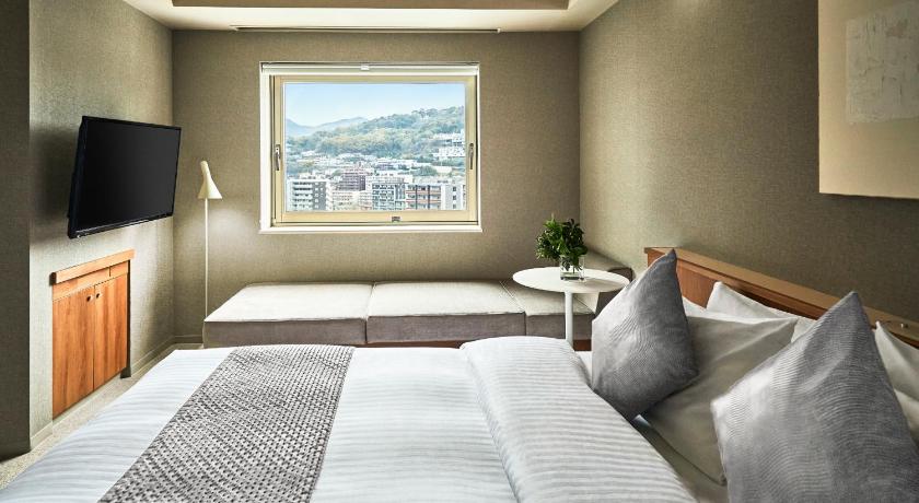 a hotel room with a bed and a television, The New Hotel Kumamoto in Kumamoto