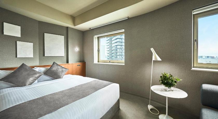 a hotel room with a bed and a desk, The New Hotel Kumamoto in Kumamoto