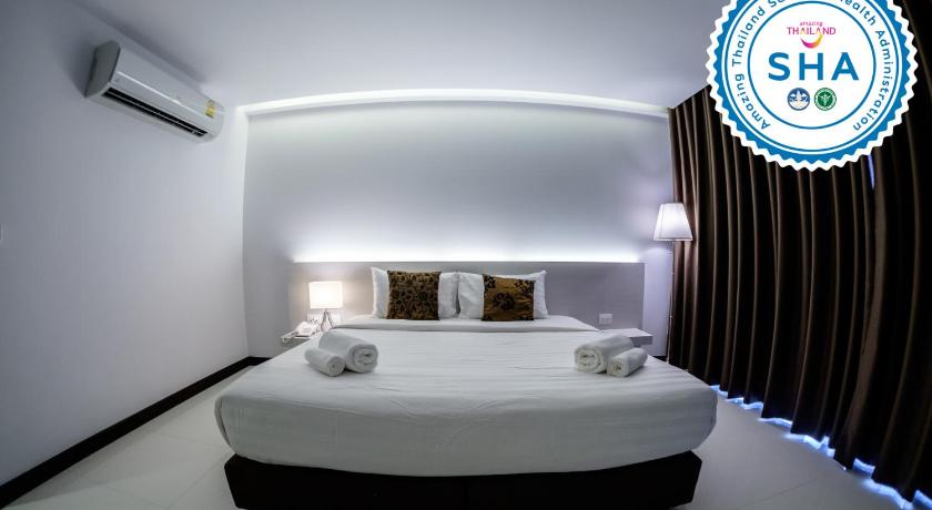 a hotel room with a white bed and white walls, Chaisaeng Villa (SHA Plus+) in Sing Buri