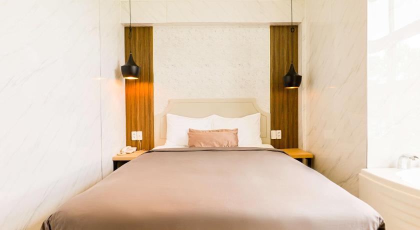 a bedroom with a bed and a dresser, La Hotel Q10 in Ho Chi Minh City