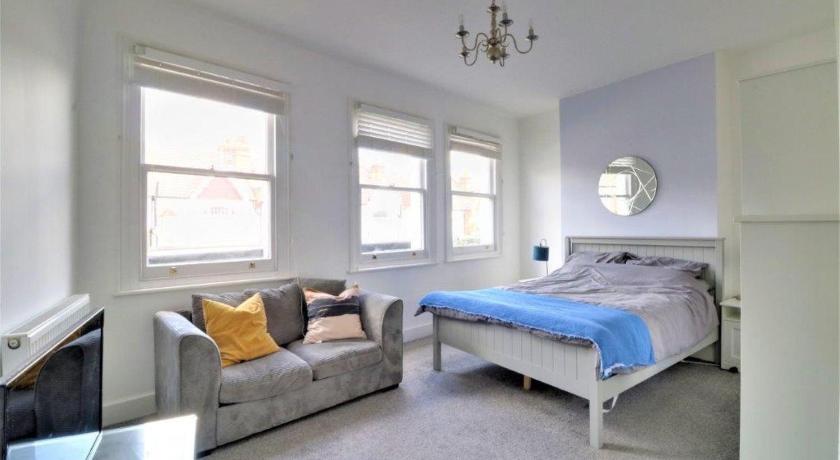a bedroom with a bed and a window, Replingham Road Apartment in London