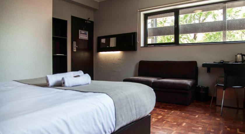 a bedroom with a bed, chair and a window, Morningstar Express Hotel in Pretoria