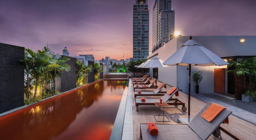 a row of tables with umbrellas in front of a city, Radisson Suites Bangkok Sukhumvit (SHA Plus+) in Bangkok