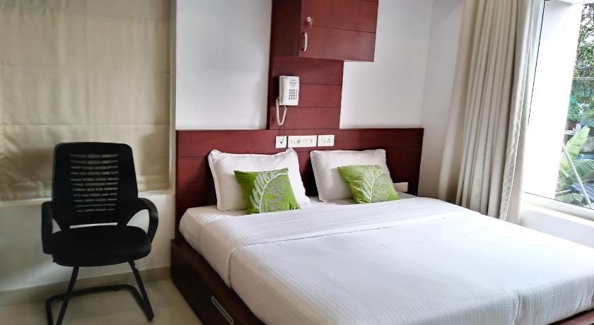 a bed room with a white bedspread and a white comforter, Omnest in Kochi