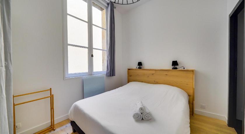 a white bed sitting in a bedroom next to a window, Nice apartment for 2 in historical center in Bordeaux