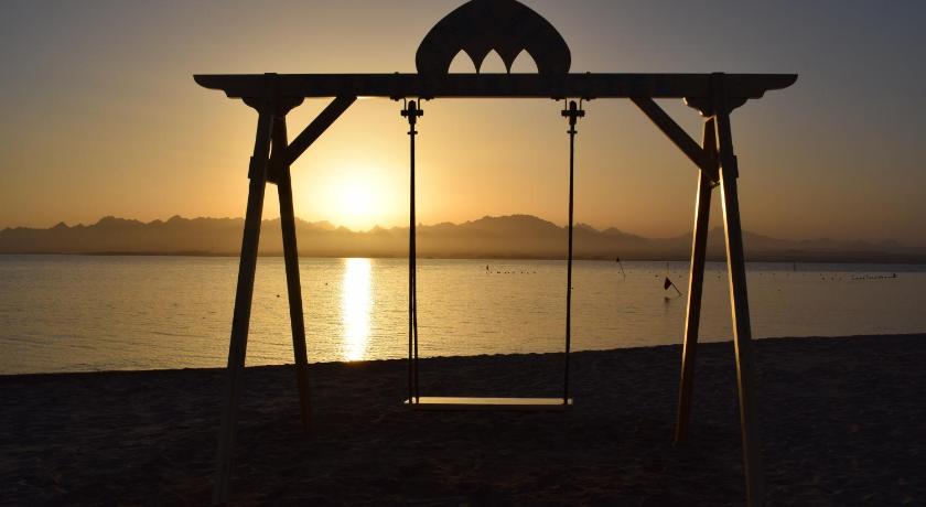 a wooden bench sitting on top of a sandy beach, Kempinski Hotel Soma Bay in Hurghada