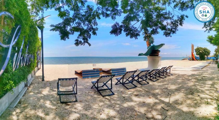 a picnic table and chairs on a beach near a body of water, Beach Walk Boutique Resort in Chonburi