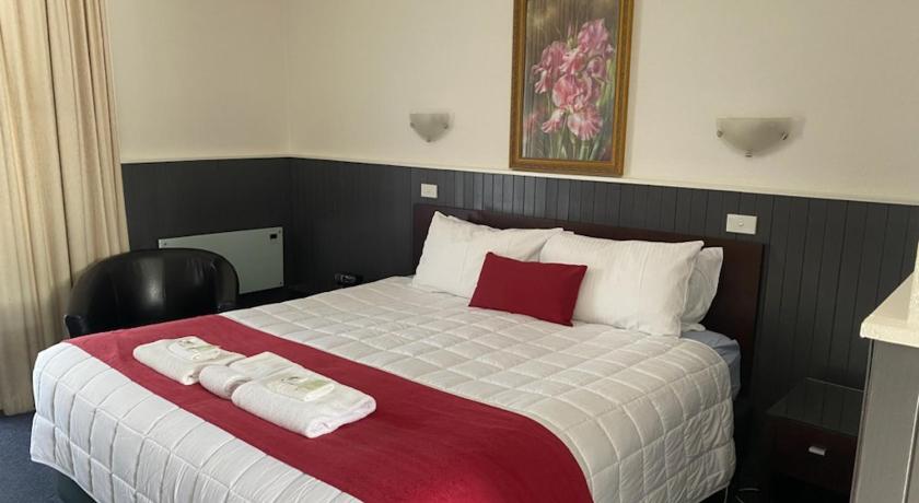 a bed room with a white bedspread and pillows, The Esplanade Motel in Lakes Entrance