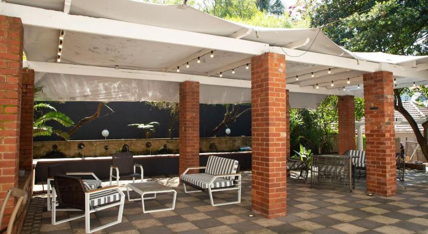 a patio area with chairs, tables and umbrellas, The Saint James on Venice in Durban