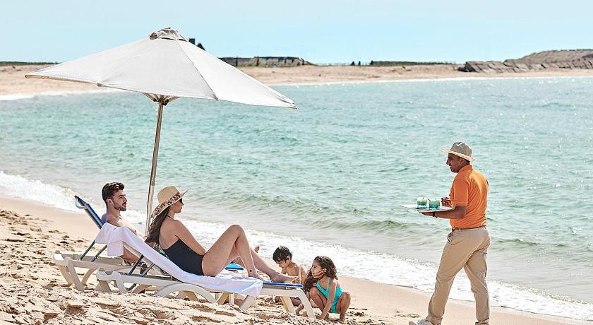 people sitting on a beach with umbrellas, Four Seasons Hotel Alexandria in Alexandria