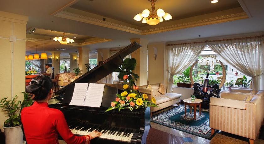 a woman playing a piano in front of a christmas tree, First Hotel in Ho Chi Minh City