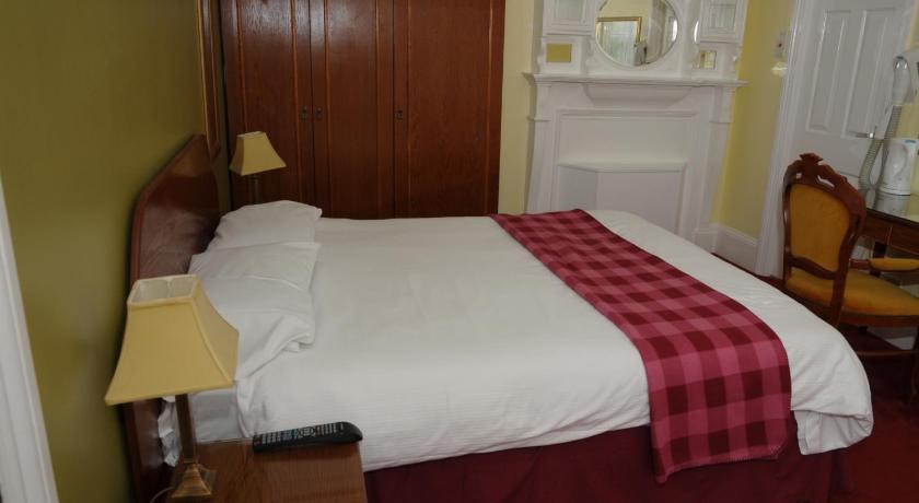 a bedroom with a bed and a dresser, Wimblehurst Hotel in Horsham