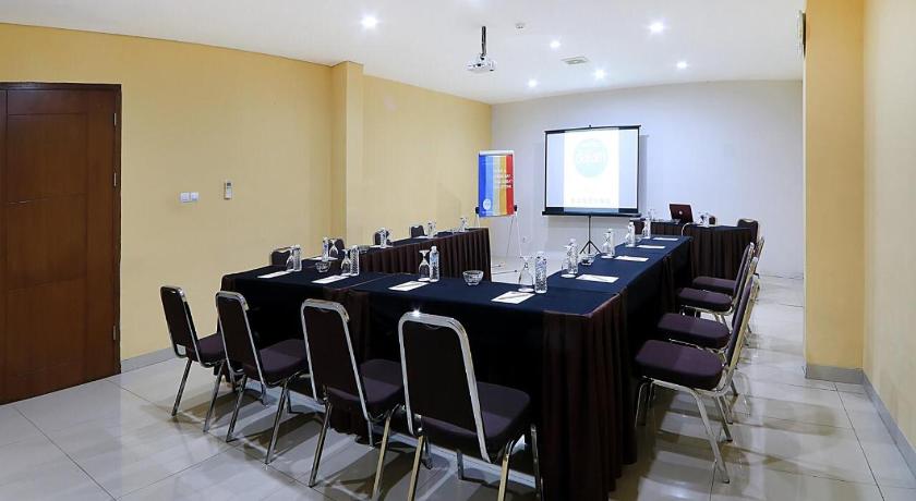 a room filled with tables and chairs and a projector screen, Hotel Dafam Rio in Bandung