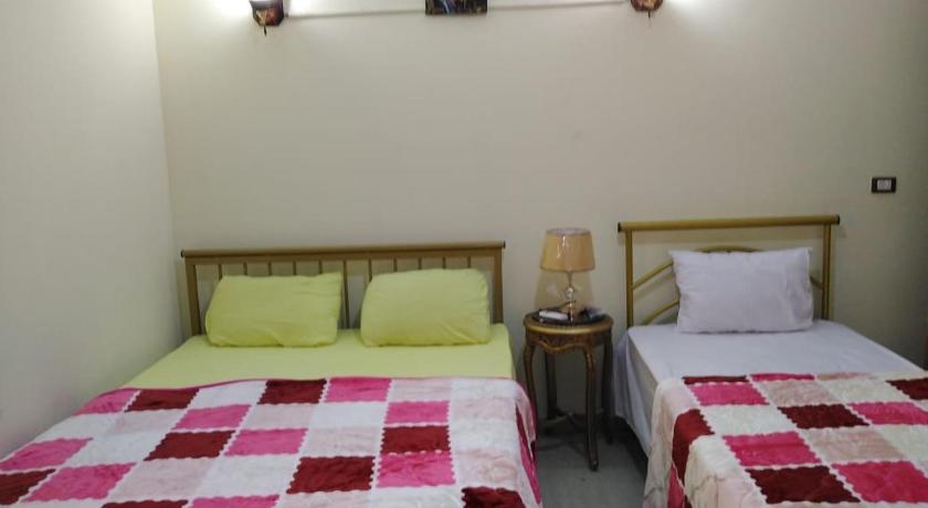 two beds in a room with two lamps on, Cairo Lodge Hostel in Cairo