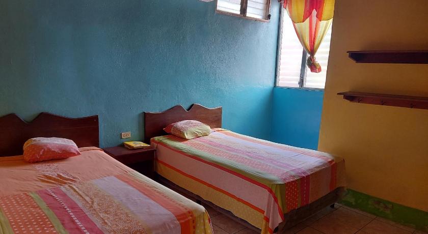 two beds in a room with a blue wall, Hotel Posada Tayazal in Flores