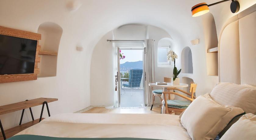 a bedroom with a bed, chair and a window, Katikies Kirini Santorini - The Leading Hotels Of The World in Santorini