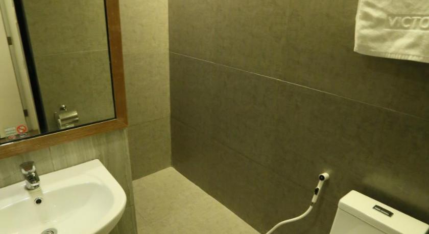 a bathroom with a toilet, sink and mirror, Hotel Ava Cuneta in Manila