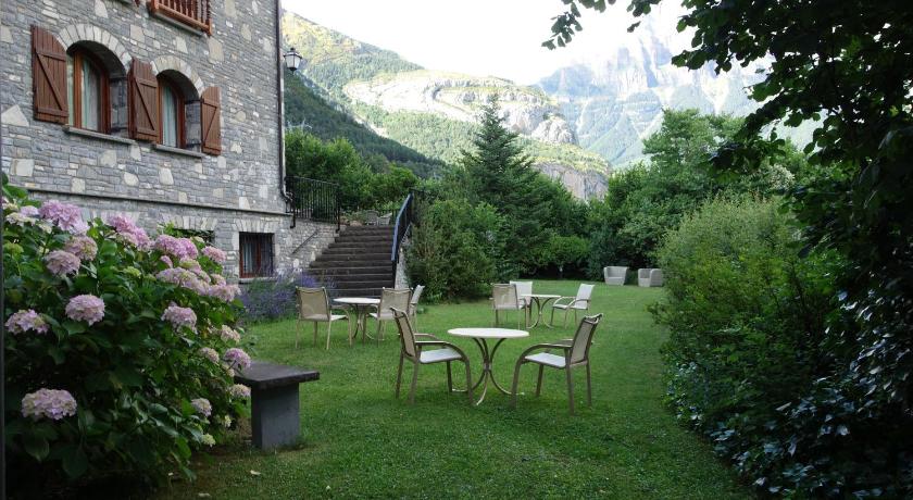 a green lawn chair sitting in front of a garden, Hotel Abetos in Torla