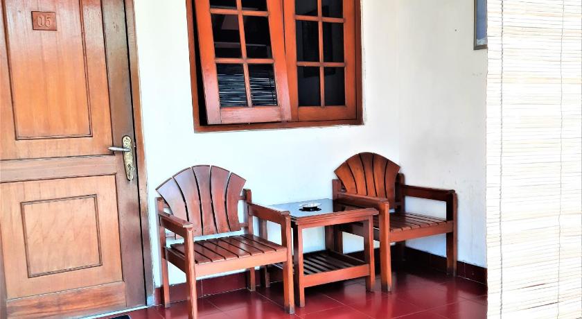 a wooden chair sitting in front of a wooden door, Hotel Perdana in Klaten