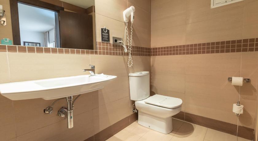 a white toilet sitting next to a sink in a bathroom, Hotel Alda Zaragoza Independencia in Zaragoza