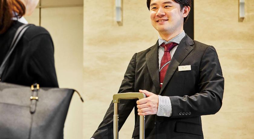 a man in a suit holding a piece of paper, HOTEL KEYAKI GATE TOKYO FUCHU in Chofu