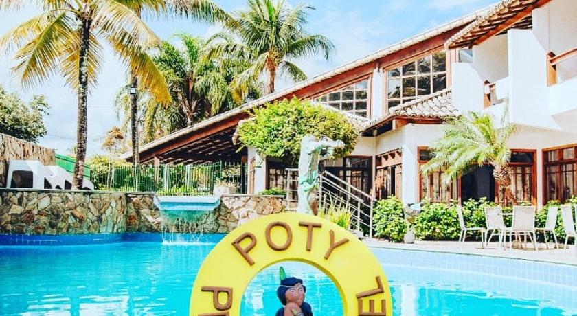 a man is swimming in a pool with a yellow frisbee, Poty Praia Hotel in Porto Seguro