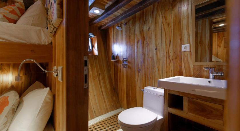 a bathroom with a toilet and a bed, Plataran Phinisi Felicia, a Luxury Private Cruise in Labuan Bajo