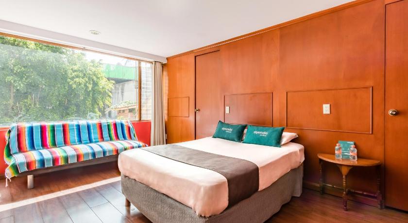 a bedroom with a bed, chair, and a window, Ayenda Suites Cuija in Mexico City