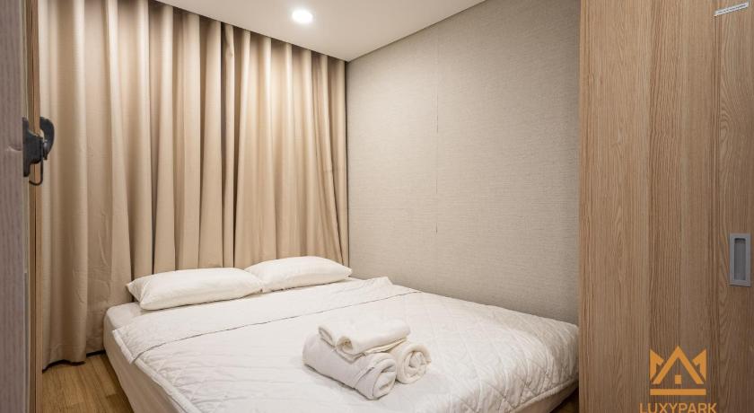 a white bed with a white comforter and pillows, Luxy Park Hotel & Apartments-City Centre in Ho Chi Minh City