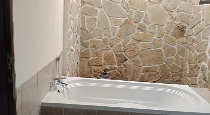 a white bath tub sitting next to a stone wall, Vila Dalia Puncak Nb3-8 in Puncak