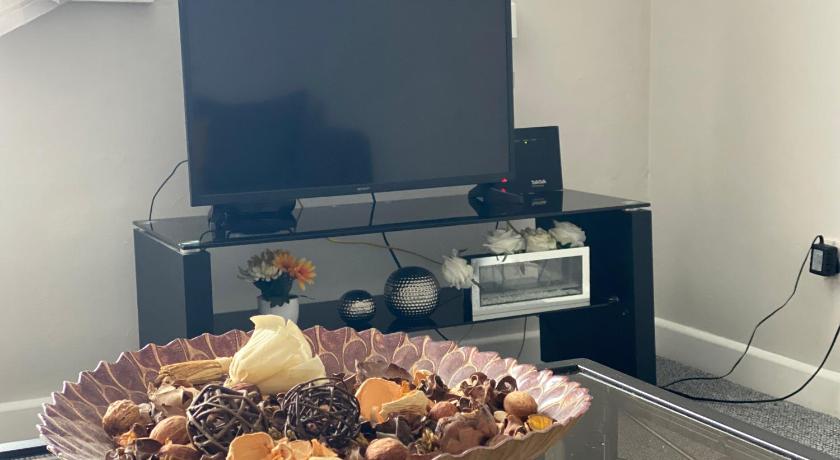 a bowl of fruit sits on a table in front of a television, Solihull apartment in Birmingham