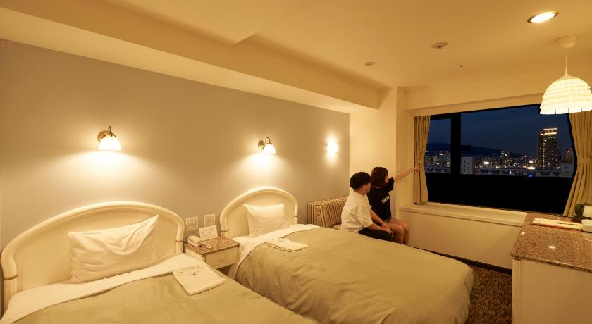 a woman sitting on a bed in a hotel room, Kobe Sannomiya Union Hotel in Kobe