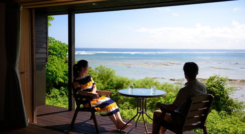 two people sitting on a bench looking out at the ocean, Villa SACHIIBARU in Okinawa Main island