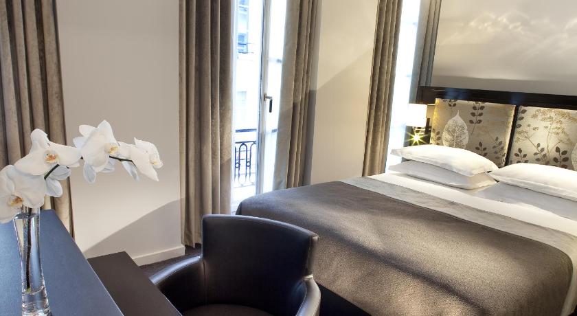 a hotel room with a bed and a chair, Hotel Caron in Paris