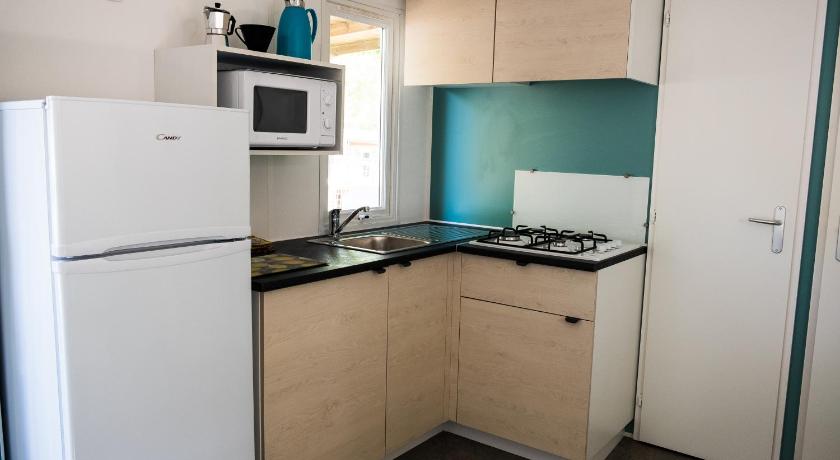 a kitchen with a refrigerator, stove, microwave and sink, Happy Camp Mobile Homes in Camping Laguna Village in Caorle