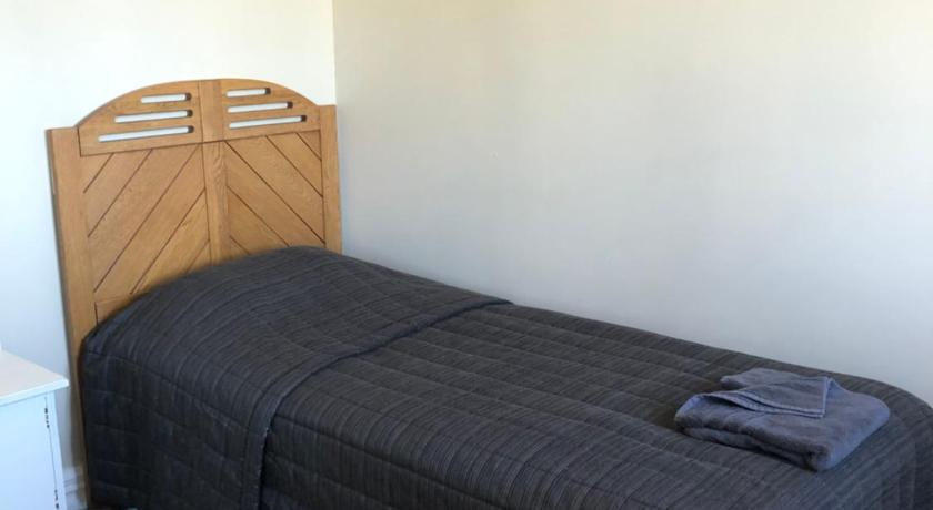 a bed in a room with a wooden headboard, Ataahua Homestay in Feilding
