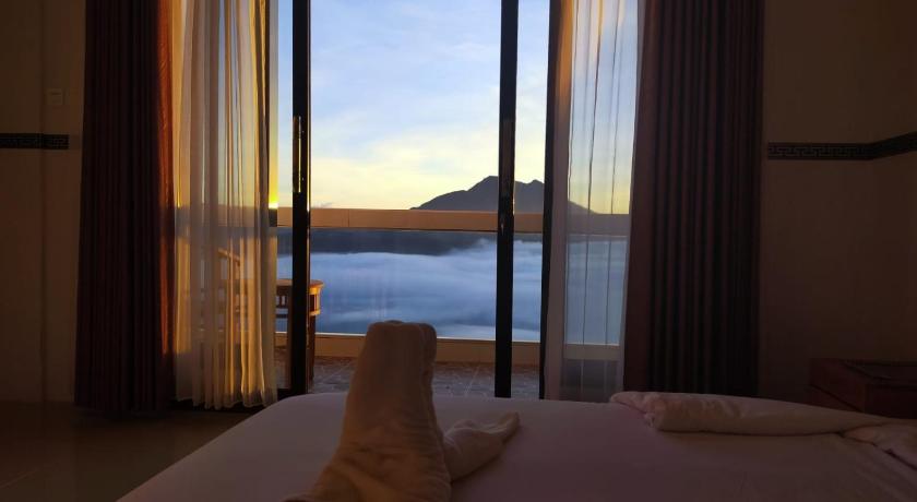 a bed sitting in front of a window with a view of the ocean, Batur view Homestay in Bali