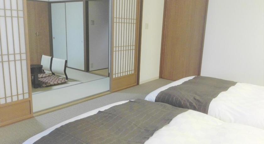 a bedroom with a bed and a mirror, Hotel Mahoroba in Noboribetsu