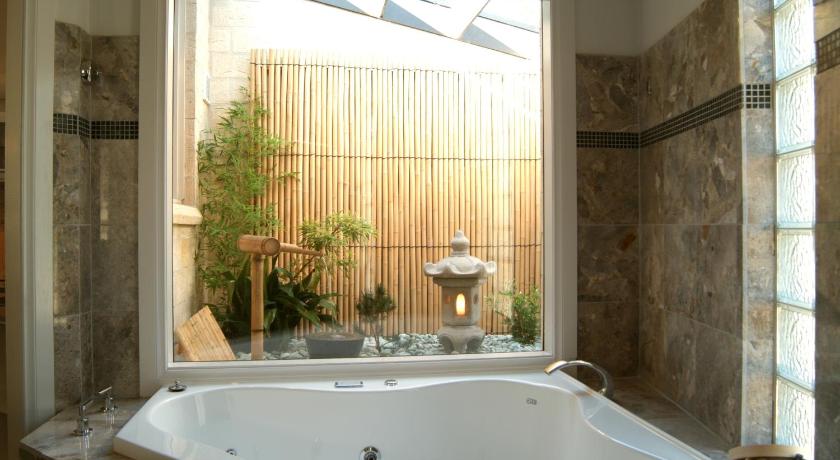 a bath tub sitting next to a window in a bathroom, The Gatehouse at Villa Raedward in Yarra Valley
