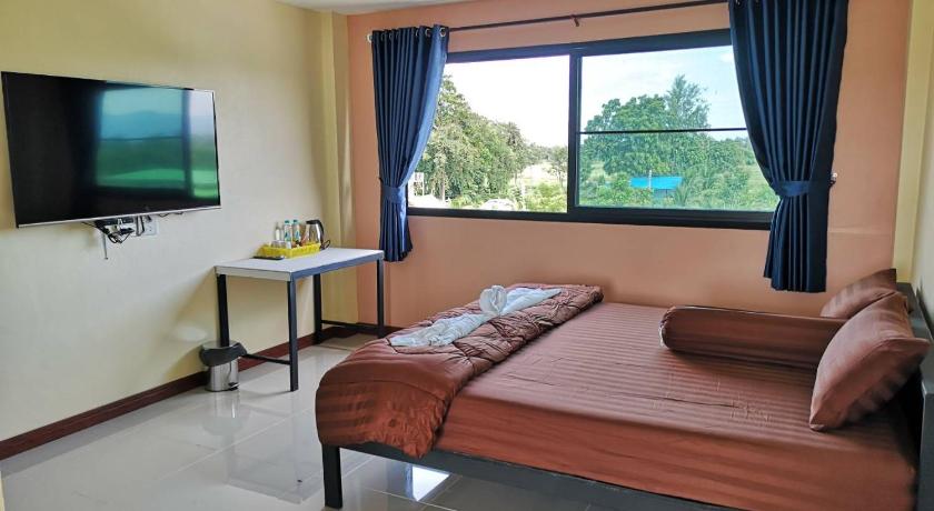 a hotel room with a bed, tv, and a window, BN Resort in Uthai Thani
